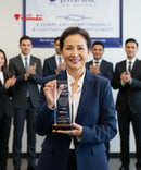 Woman in a blue suit holding an award with people clapping in the background, featuring a trophy shop advertisement.