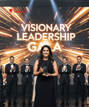 Woman holding an award on a stage with 'Visionary Leadership Gala' text and trophy logo.