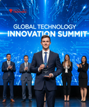 Man holding an award on stage at the Global Technology Innovation Summit with a blue circuit board background.