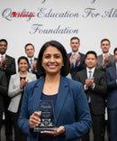 Woman holding an award in front of a group of people with 'Quality Education For All' foundation text.