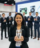Woman holding an award in front of a group of people in a formal setting