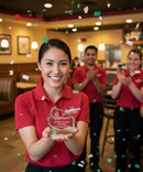 Person in a red Applebee's shirt holding an award with colleagues clapping in the background.