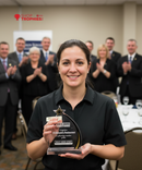 Woman holding an award in a room with people clapping