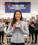 Woman holding a trophy with clapping colleagues in the background, featuring Forbes Canada's Best Employers banner.